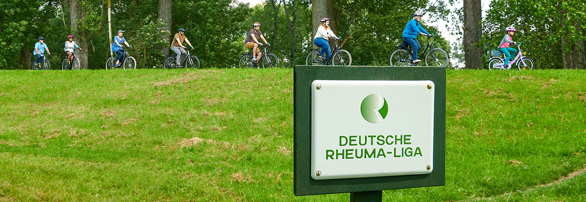 Gruppe Radfahrender, im Vordergrund Schild mit der Aufschrift "Deutsche Rheumaliga Bundesverband"